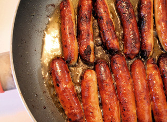 Golden Brown Sausages Frying In Skillet
