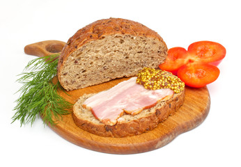 Bread with ham, mustard, dill and tomato on the wood plate