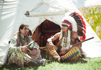 North American Indians sit at a wigwam
