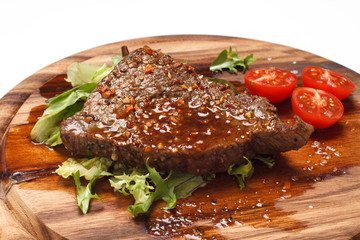 Grilled steak with tomato on wooden background