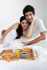 Obraz na płótnie Canvas Couple eating breakfast in bed