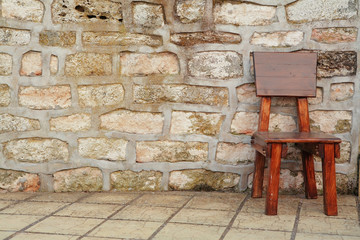 wooden brown chair against stone wall