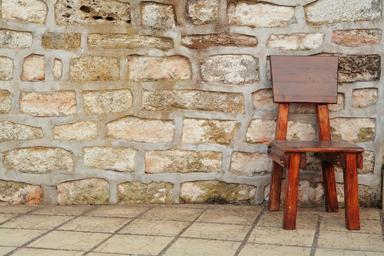 Wooden Brown Chair Against Stone Wall