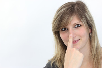 Blonde Frau drückt ihren linken Zeigefinger auf ihre Nase