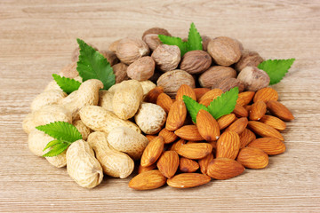 nutmeg, peanuts and almonds on wooden background
