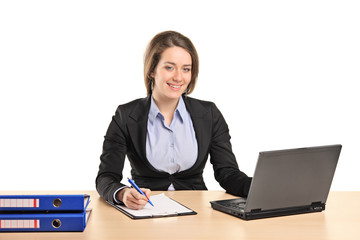 A smiling young businesswoman working on a laptop