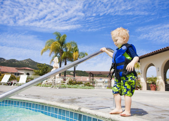 Little Boy Cautiously Stepping into Outdoor Pool