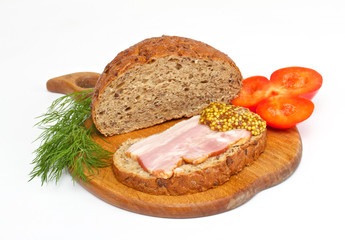 Bread with ham, mustard, dill and tomato on the wood plate