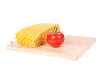 Lasagna pasta and tomatoon cutting board