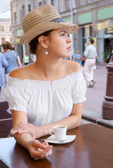 Young pretty woman in street cafe with cup