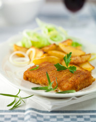 Breaded fish fillet with roasted potatoes and fresh herbs