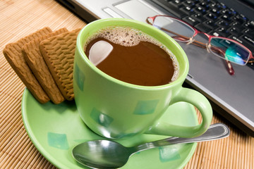cup of hot cacao, biscuits  and computer.