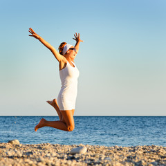 Fototapeta na wymiar happy young woman is jumping in the beach