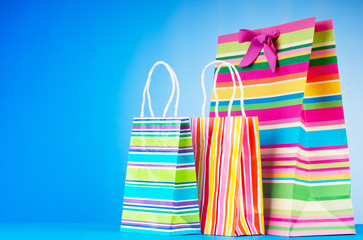 Colourful paper shopping bags against gradient background