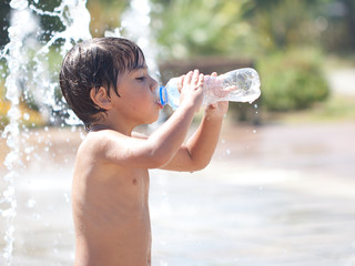 bambino bagnato che beve acqua dalla bottiglietta