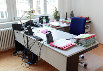 Schreibtisch im Büro mit Akten und moderner Bürotechnik