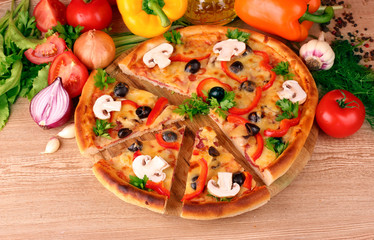 pizza and vegetables on wooden background