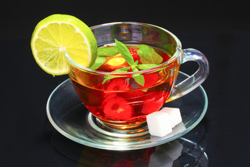 black tea, raspberry, lime and mint in cup on black background