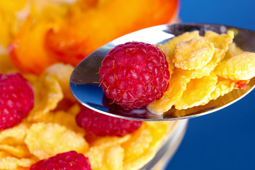 tasty cornflakes and fruit  in glass bowl on blue background