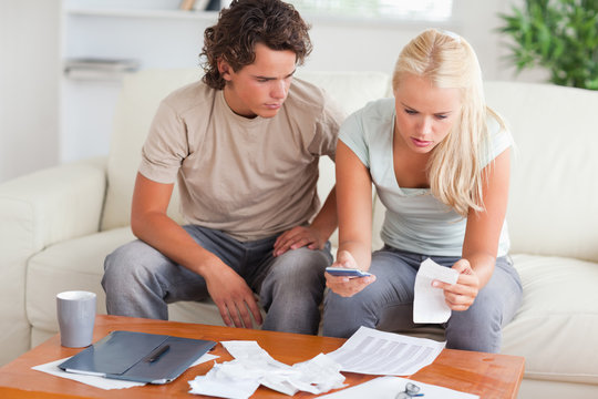 Shocked couple calculating their expenses