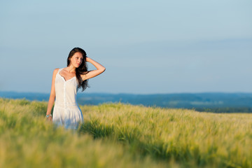 Fototapeta na wymiar Sunset corn field beautiful brunette woman walk