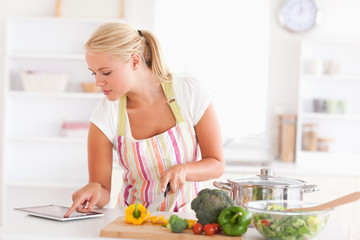 Obraz na płótnie Canvas Blonde woman using a tablet computer to cook