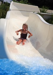 Small girl sliding down a white water slide.