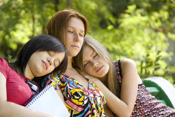Fototapeta na wymiar Three girlfriends doing homework at the park.