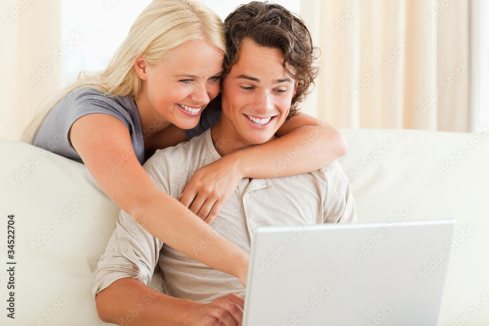 Poster smiling couple using a laptop