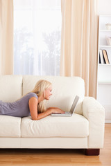 Fototapeta premium Portrait of a woman lying on a couch using a notebook