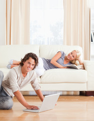 Portrait of a man with a laptop while his girlfriend is with a b