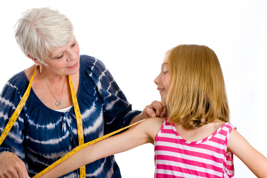 Mature Woman Measuring Child For Clothes