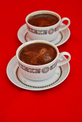 Two cups of coffee isolated on red