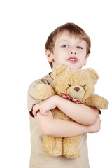 Boy in the beige t-shirt hugs bear-toy and says something.