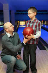 Fototapeta premium Father gives son red ball for bowling