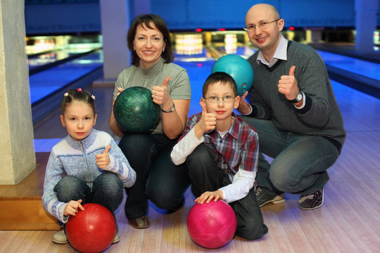 Family of squatting in bowling club and shows hands of ok