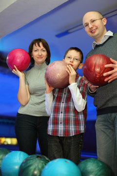 Family stand alongside and hold balls for bowling