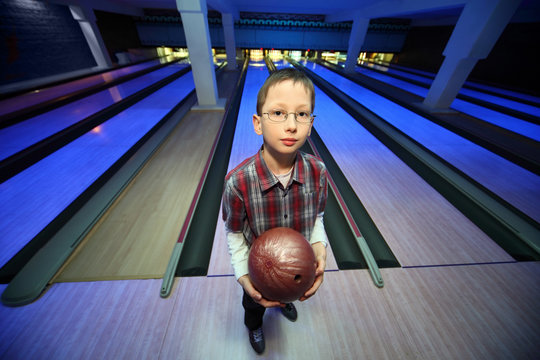 Boy stands with  ball for bowling and looks ahead
