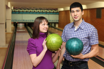 Fototapeta premium Girl and youth stand with balls for bowling, girl looks at man