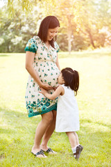 Girl kissing pregnant mother