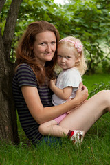 mother with daughter on a grass at the garden