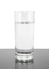Glass of clean water on white- gray background.
