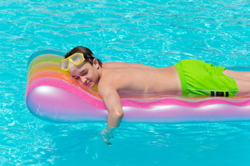 Boy resting on lilo in pool