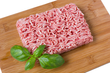 minced meat with basil on a wooded cutting board