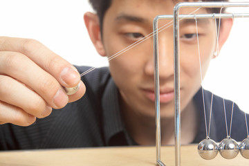 man moving Newton balls in office