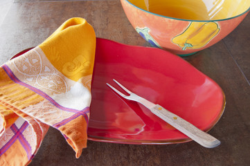 Colorful red platter and bowl with napkin and fork