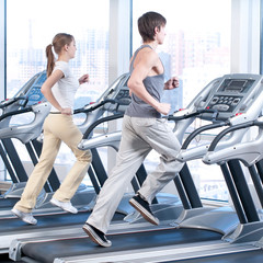 Fototapeta na wymiar Young woman and man at the gym exercising. Running