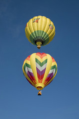 Two hot-air balloons flying vertically aligned