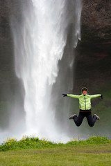 tourist jumping in front of Seljalandsfoss waterfall, Iceland