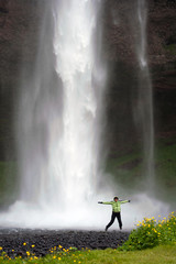 woman jumping near Seljalandsfoss waterfall, Iceland